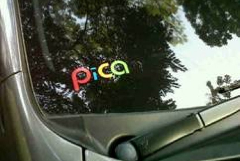 Stiker PiCA warna-warni ditempel di pojok kiri bawah pada kaca depan mobil.