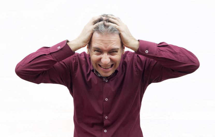 Seorang karyawan pria memegang kepalanya karena stres (ilustrasi). Tuntutan pekerjaan yang tinggi dapat memicu gangguan mental.