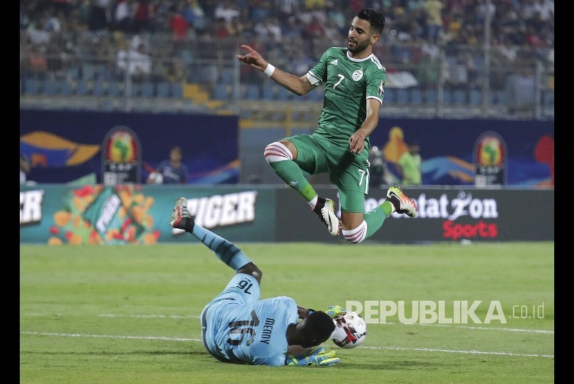 Striker Aljazair Riyad Mahrez melompati kiper Senegal Edouard Osoque Mendy  pada pertandingan Grup C Piala African antara Aljazair dan Senegal di Kairo, Jumat (28/6). 