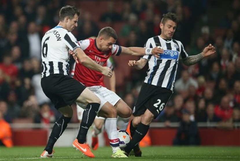 Striker Arsenal, Lukas Podolski, di tengah kepungan para pemain Newcastle United pada laga lanjutan Liga Primer Inggris.