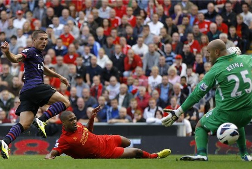 Striker Arsenal, Lukas Podolski (kiri), melepaskan tembakan menjebol gawang kiper Liverpool, Pepe Reina (kanan), di laga Liga Inggris di Stadion Anfield, Liverpool, Ahad (2/9). 