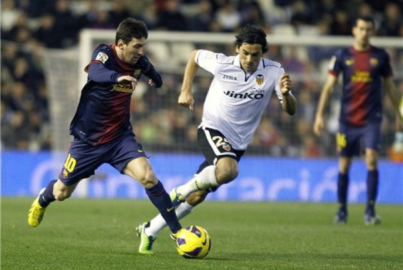 Striker Barcelona, Lionel Messi (kiri), berusaha melepaskan diri dari penjagaan pemain Valencia, Tino Costa, dalam laga La Liga Spanyol di Stadion Mestalla, Valencia, Ahad (3/2). 