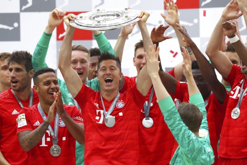 Striker Bayern Muenchen, Robert Lewandowski (tengah) mengangkat trofi Bundesliga musim 2018/2019.