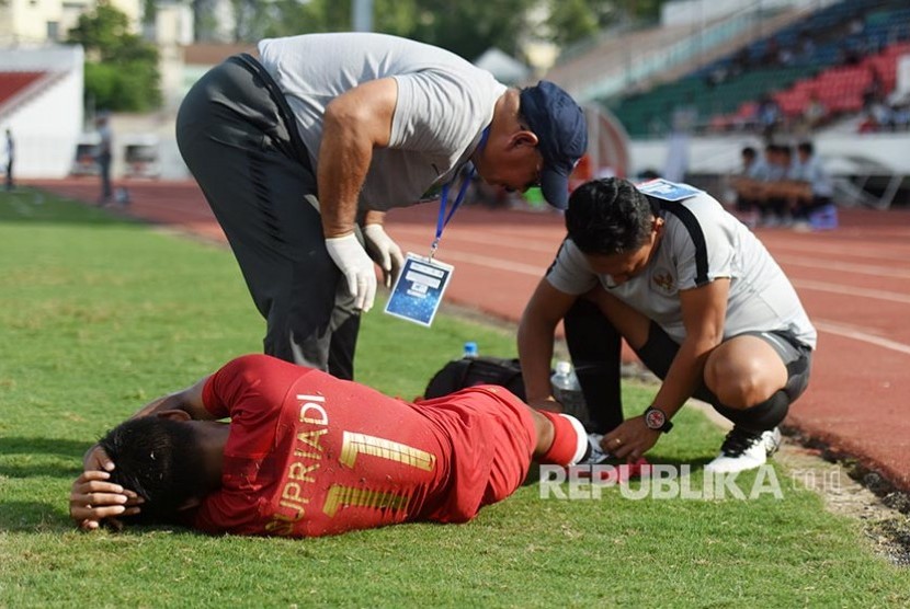 Striker Indonesia Supriadi (bawah) mendapat perawatan dari tim medis  pada laga penyisihan Grup A Piala AFF U-18 2019 di Stadion Thong Nhat, Ho Chi Minh, Vietnam, Senin (12/8)