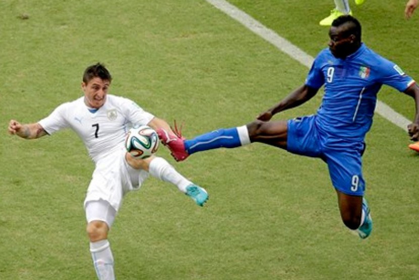 Striker Italia Mario Balotelli (kanan) saat berduel dengan pemain Uruguay Cristian Rodriguez 