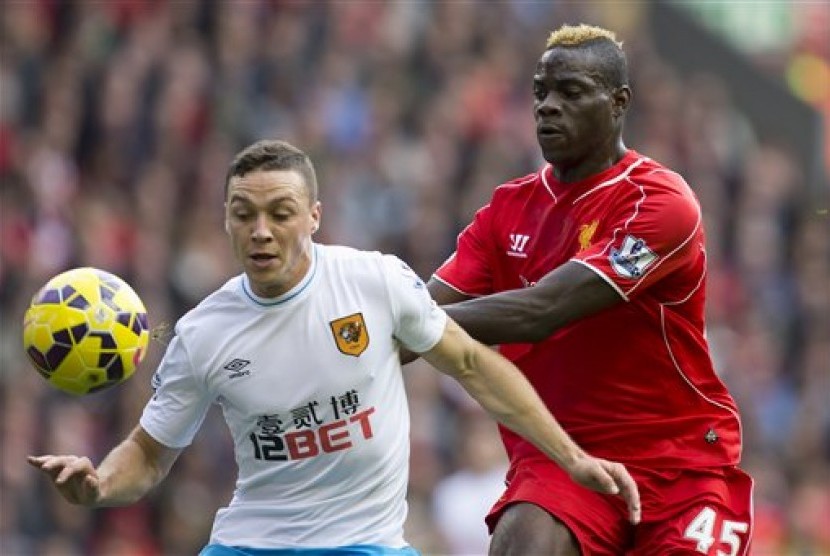 Striker Liverpool Mario Balotelli (kanan) berduel bola dengan pemain Hull City dalam pertandingan Liga Primer Inggris di Anfield, Sabtu (25/10).