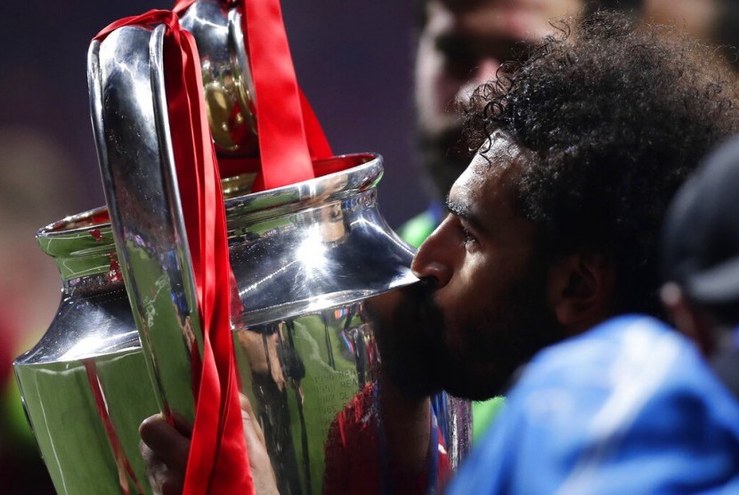 Striker Liverpool, Mohamed Salah mencium trofi Liga Champions.