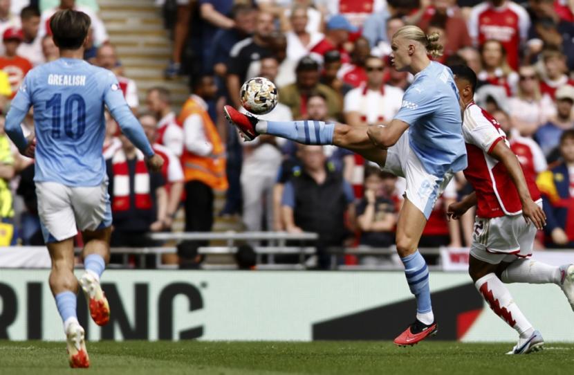 Striker Manchester City Erling Haaland (tengah) beraksi di tengah bayangan pemain Arsenal pada laga Community Shield, Ahad (6/8/2023). Arsenal juara setelah menang adu penalti 4-1 atas Man City.