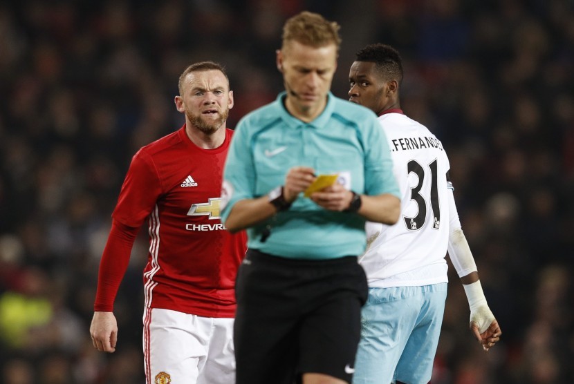 Striker Manchester United, Wayne Rooney (kiri) terlihat kesal setelah dikartu kuning oleh wasit Mike Jones pada laga Piala Liga lawan West Ham United di Old Trafford, Kamis (1/12) dini hari WIB. United menang 4-1 pada laga ini.