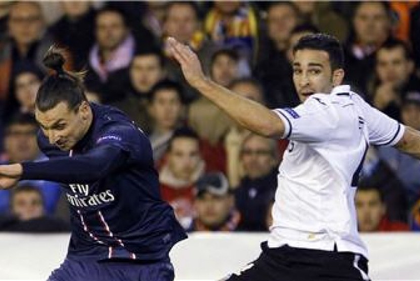 Striker Paris Saint-Germain, Zlatan Ibrahimovic (kiri), berduel dengan pemain Valencia, Adil Rami, di leg pertama babak 16 besar Liga Champions di Stadion Mestalla, Valencia, Selasa (12/2).  