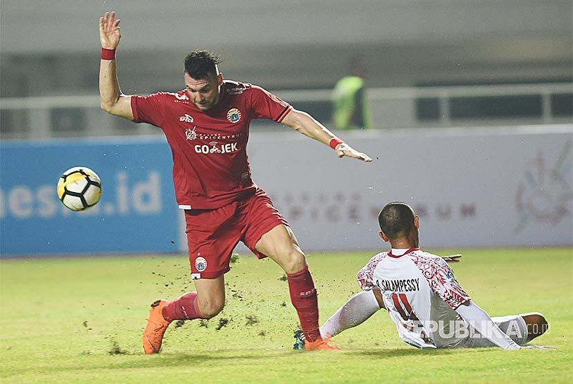 Striker Persija Jakarta Marko Simic (kiri) mencoba melewati hadangan pesepak bola Persipura Jayapura Ricardo Salampessy (kanan) dalam laga lanjutan Liga 1 di Stadion Pakansari, Bogor, Jumat (25/5).