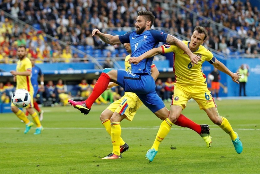 Striker Prancis Olivier Giroud (biru) dijaga pemain Rumania Vlad Chiriches.