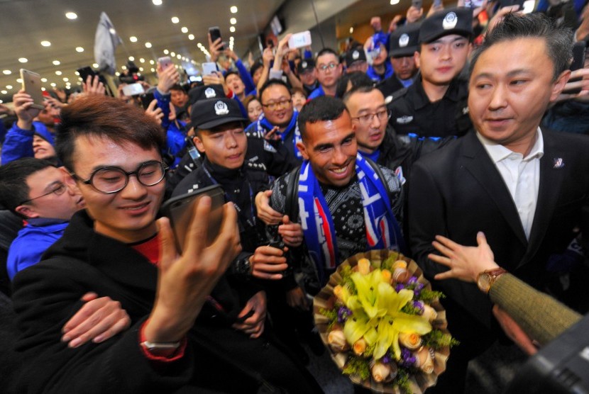 Striker Shanghai Shenhua, Carlos Tevez (tengah) berjalan menembus kerumuman fan yang menyambut kedatangannya di Bandara Internasional Shanghai, Kamis (19/1). Tevez baru dibeli Shenhua dari Boca Juniors.
