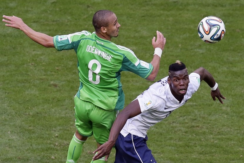 Striker timnas Nigeria, Peter Odemwingie (kiri) berebut bola dengan Paul Pogba pada laga Piala Dunia 2014. Odemwingie tengah diincar Madura United. 