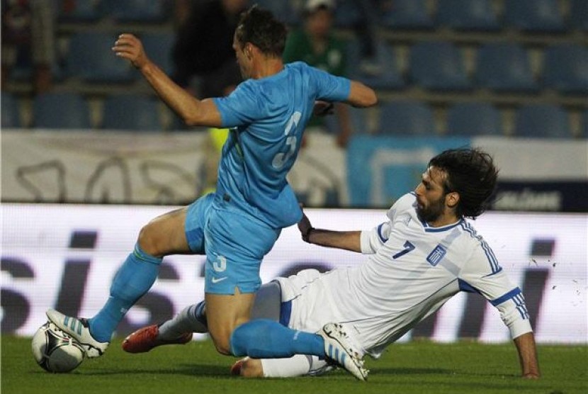 Striker timnas Yunani, Georgios Samaras (kanan), berebut bola dengan pemain Slovenia, Dejan Kelhar, dalam laga uji coba di Kufstein pada 26 Mei lalu. 