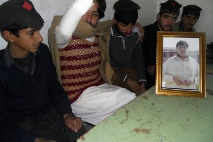 Students and brother sit next to a framed portrait of Aitezaz Hassan in a classroom at the Government High School Ibrahim Zai in Hangu district, bordering North Waziristan January 10, 2014.