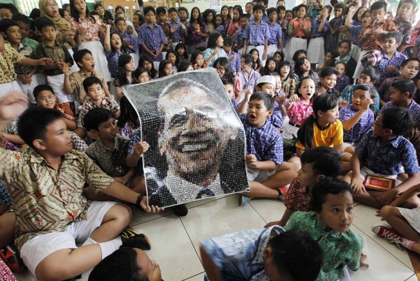Students at State Elementary School Menteng 01, where U.S. President Barack Obama studied from 1970-1971, hold a poster with an image of Obama while watching TV coverage of the U.S. presidential election in Jakarta November 7, 2012.   