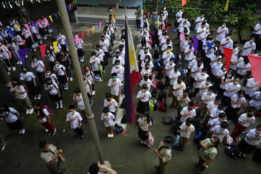 Students attend a flag raising ceremony during the opening of classes at the San Juan Elementary School in Pasig, Philippines on Monday, Aug. 22, 2022. Millions of students wearing face masks streamed back to grade and high schools across the Philippines Monday in their first in-person classes after two years of coronavirus lockdowns that are feared to have worsened one of the world