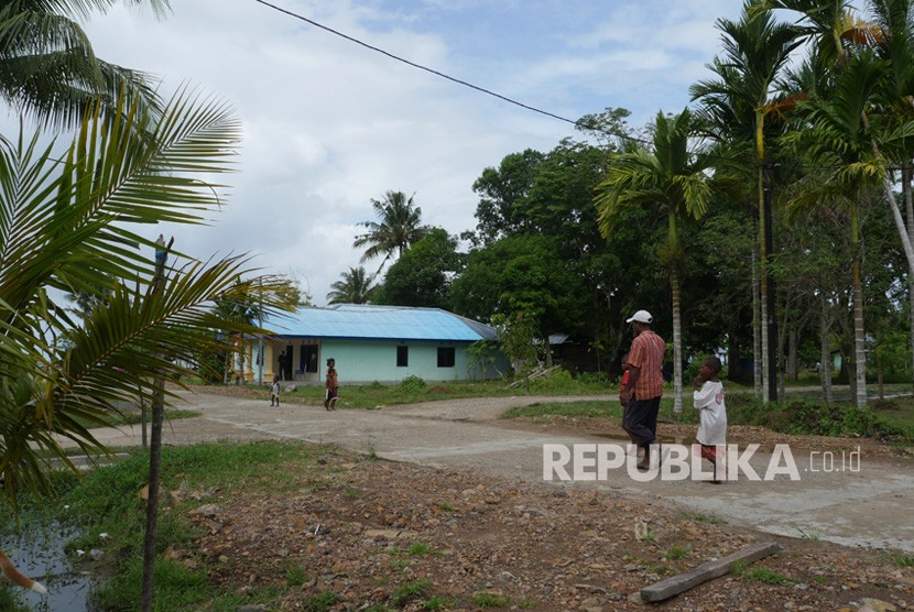 Wellem Kalami sedang meniup un untuk memgumpulkan warga, berlatar belakang Pulau Um. Warga berkumpul untuk membangun, tetapi tidak jika harus membabat hutan. 