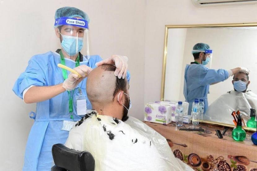Suasana salon cukur rambut di Mina pada tahun haji 2020. Tukang cukur rambut pun harus taat pada protokol kesehatan.