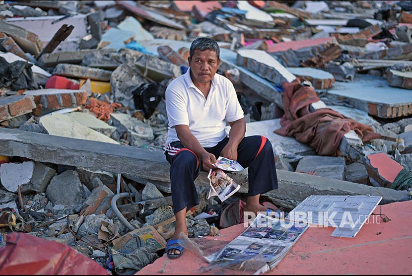 Sukur Sultan membawa foto keluarga yang meninggal akibat gempa dan tsunami di Wani, Donggala, Sulawesi Tengah.
