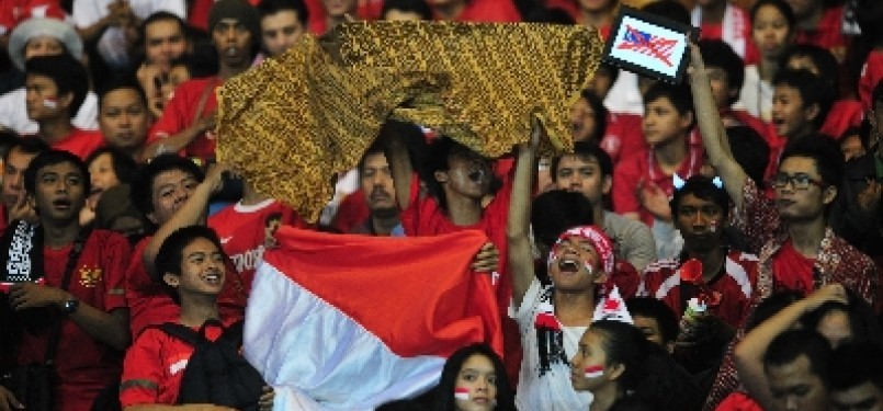 Suporter Indonesia mengacungkan kain bermotif batik dan bendera Merah Putih.