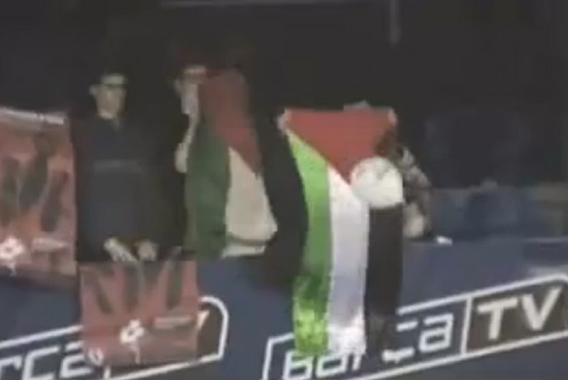 Suporter membentangkan bendera Palestina.