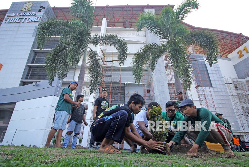 Suporter Persebaya (Bonek) menanam pohon di bagian depan Stadion Gelora Bung Tomo (GBT) saat mengikuti aksi bersih-bersih di Surabaya, Jawa Timur, Jumat (8/11/2019).