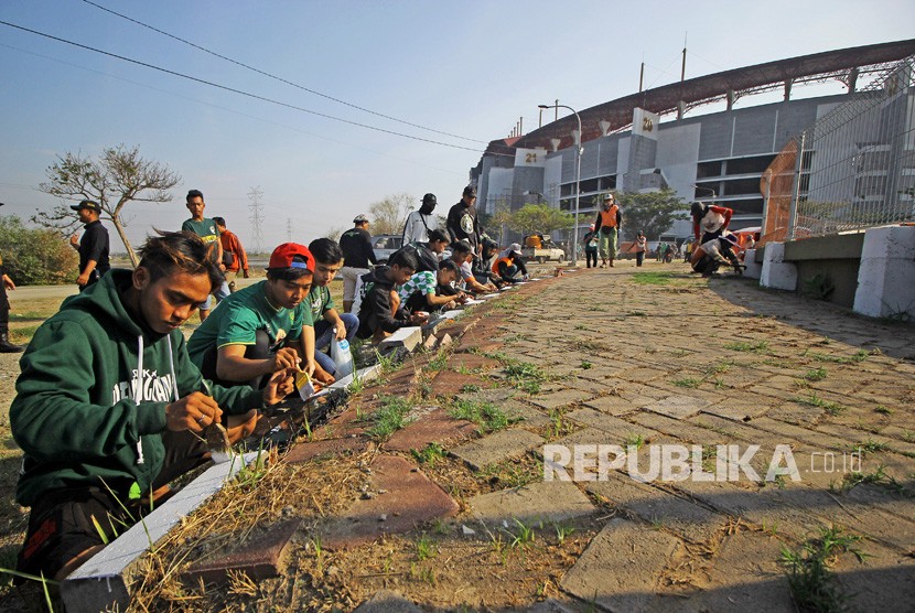 Suporter Persebaya (Bonek) mengecat tepi jalan menuju Stadion Gelora Bung Tomo (GBT). Stadion GBT menjadi salah ssatu venue Piala Dunia U-20 2021.