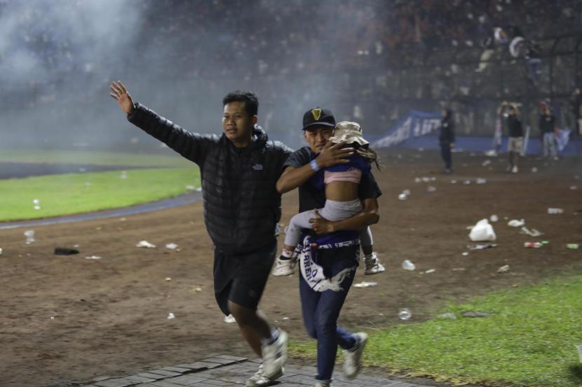 Suporter sepak bola mengevakuasi seorang anak saat bentrokan terjadi di Stadion Kanjuruhan di Malang, Jawa Timur. Kementerian PPPA mengonfirmasi ada 33 anak yang menjadi korban meninggal tragedi Kanjuruhan.