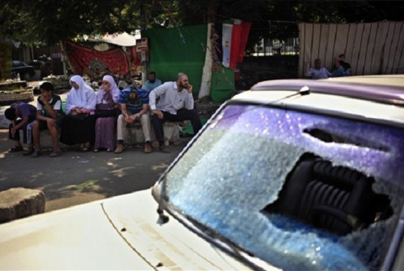 Supporters of Egypt's ousted President Mohammed Morsi sit next to a damaged car during clashes with Police, where protesters have set up a camp near Cairo University in Giza, Egypt, Tuesday, July 23, 2013. 