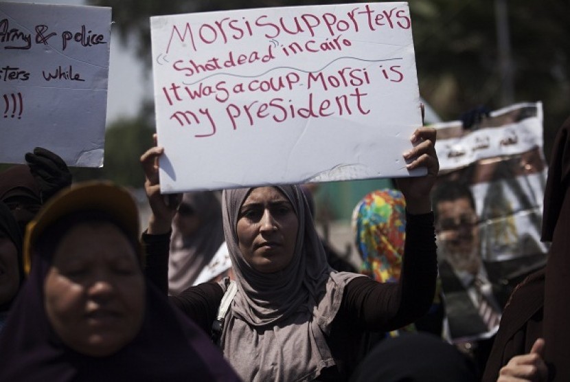 Supporters of Egypt's ousted President Mohammed Mursi hold banners denouncing the killing of Muslim Brotherhood supporters near Cairo University, where protesters have installed their camp in Giza, southwest of Cairo, Egypt, Monday, July 8, 2013. 