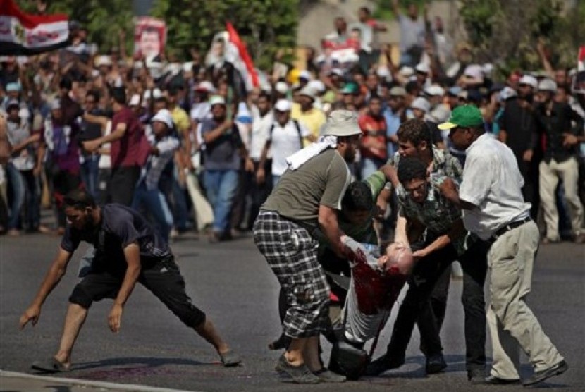 Supporters of ousted Egypt's President Mohammed Morsi pick up the body of a man shot near the Republican Guard building in Cairo, Egypt, Friday, July 5, 2013.