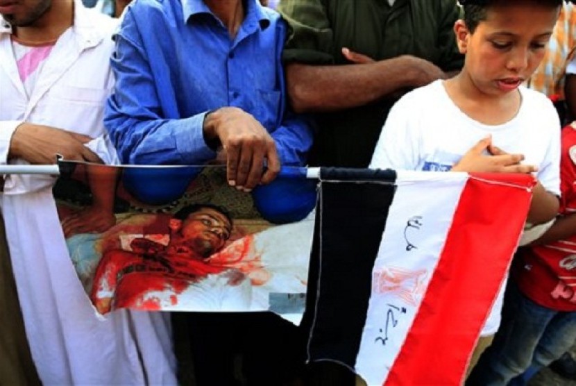 Supporters of ousted President Mohammed Mursi pray as they hold a picture of man killed during clashes with Egyptian security forces, at the Republican Guard building in Nasr City, Cairo, Egypt, Tuesday, July 9, 2013.