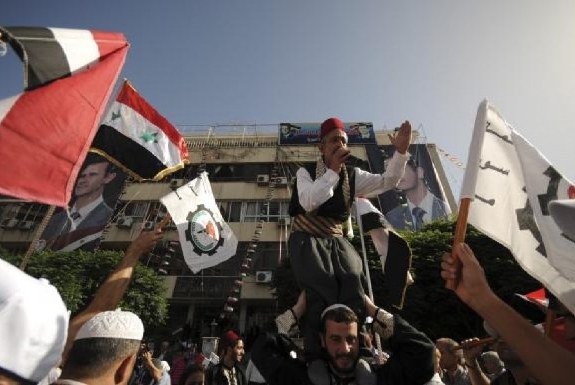 Supporters of Syria's President Bashar al-Assad wave the national flags and chant slogans in front of General Federation of Trade Unions building, during presidential election in Damascus June 3, 2014.