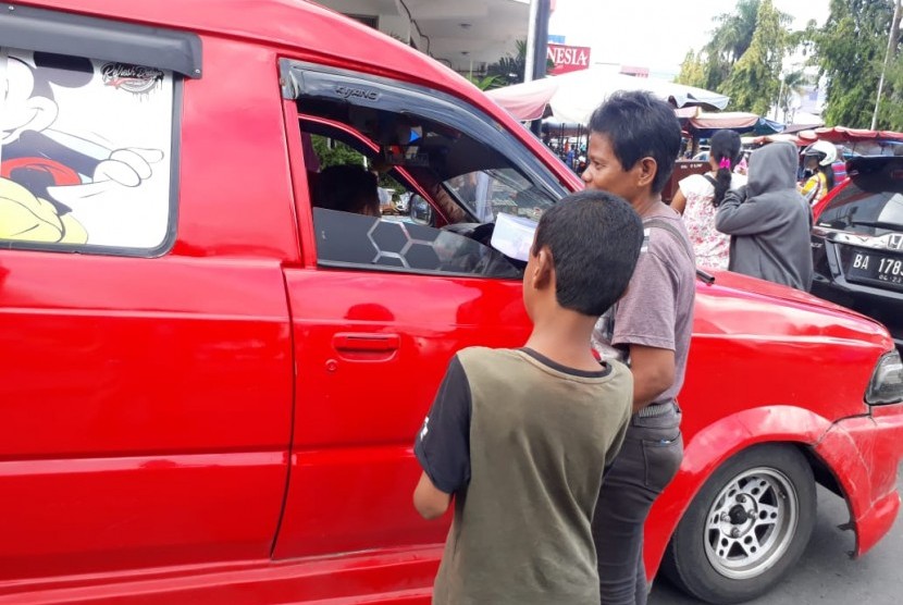 Susilawati mengajak anaknya berjualan setelah dilarang mengikat anaknya di pohon.