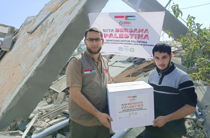 Syekh Isa Al-Herthani (kiri) saat menyerahkan bantuan untuk warga Gaza. Syekh Isa dan keluarganya wafat syahid akibat serangan zionis Israel
