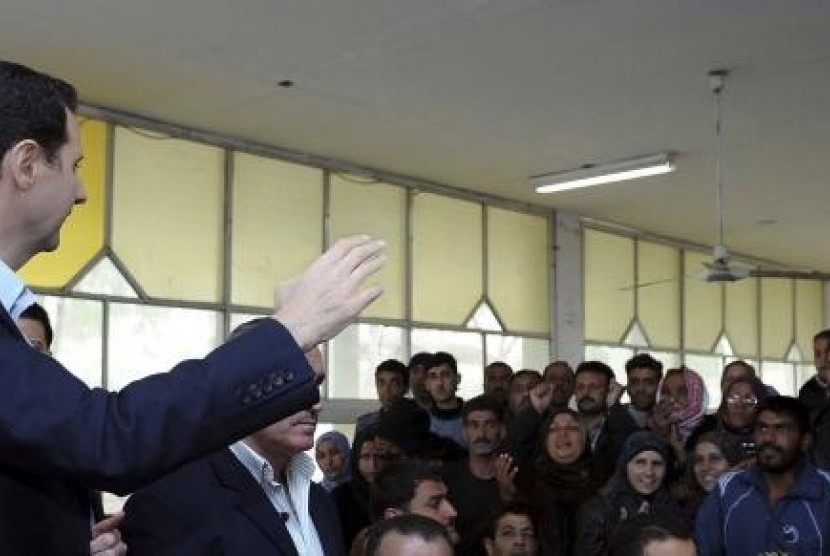 Syria's President Bashar al-Assad (left) speaks to displaced Syrians during his visit to them in the town of Adra in the Damascus countryside, March 12, 2014.