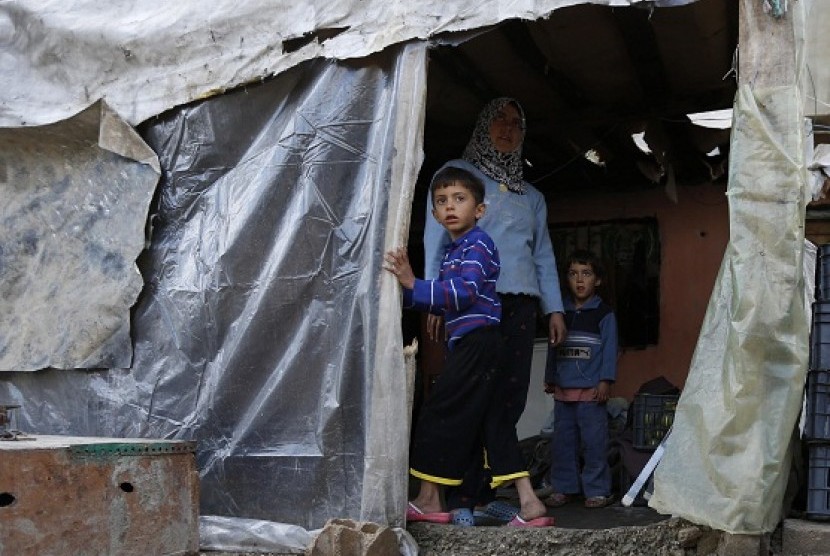 Syrian refugee Am Ahmed stands with her children at her temporary home in a garage where she lives with her family in Bar Elias village in the Bekaa valley December 13, 2012.  