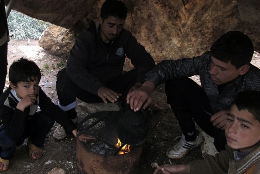 Syrian refugees warm themselves by a fire at a refugee camp in Atimeh, on the Syrian-Turkish border of the Idlib Governorate December 10, 2012. Picture taken December 10, 2012.   