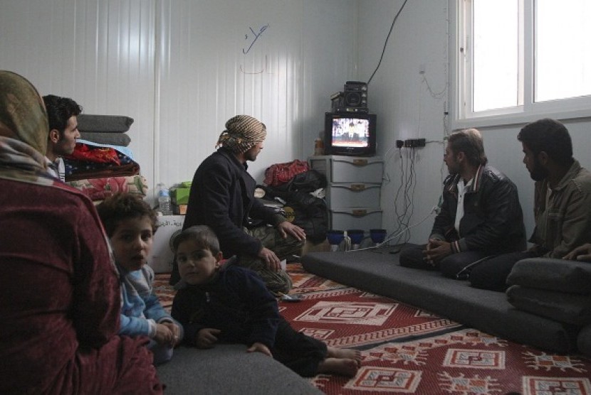 Syrian refugees watch a television broadcast of Syria's President Bashar al-Assad speaking in Damascus, in their container at the Al-Zaatari refugee camp in the Jordanian city of Mafraq, near the border with Syria, January 6, 2013.  