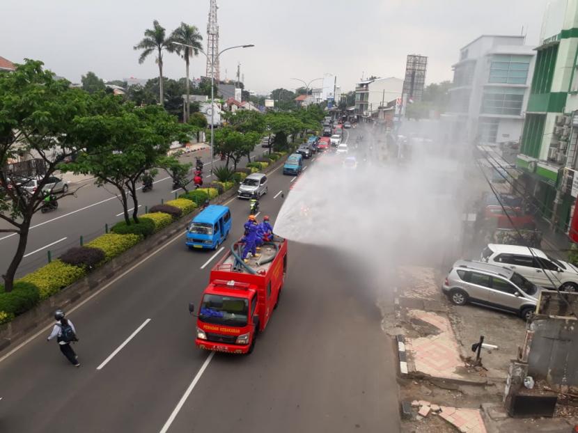 Tampak mobil damkar menyemprotkan disinfektan  di sepanjang jalan Margonda raya, Depok, Senin  (23/3)