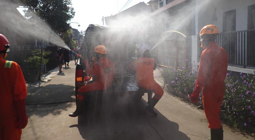 Tampak petugas dari SCRC sedang melakukan penyemprotan disinfektan ke rumah warga