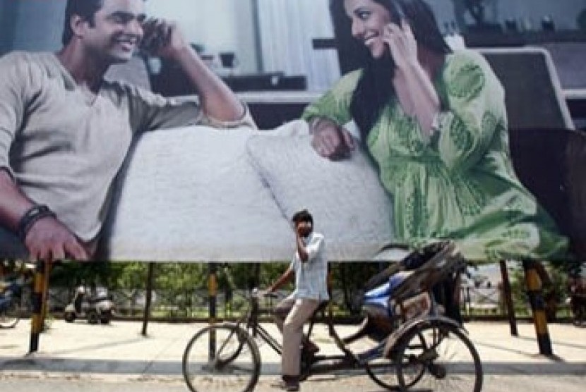 Tampak seorang pria tengah menelpon di ponsel melewati iklan telekomunikasi di India 