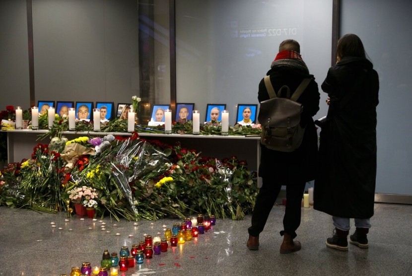 Tamu memberikan penghormatan di depan foto-foto kru pesawat Ukraine Airlines yang jatuh di dekat Teheran, Iran, Rabu (8/1).