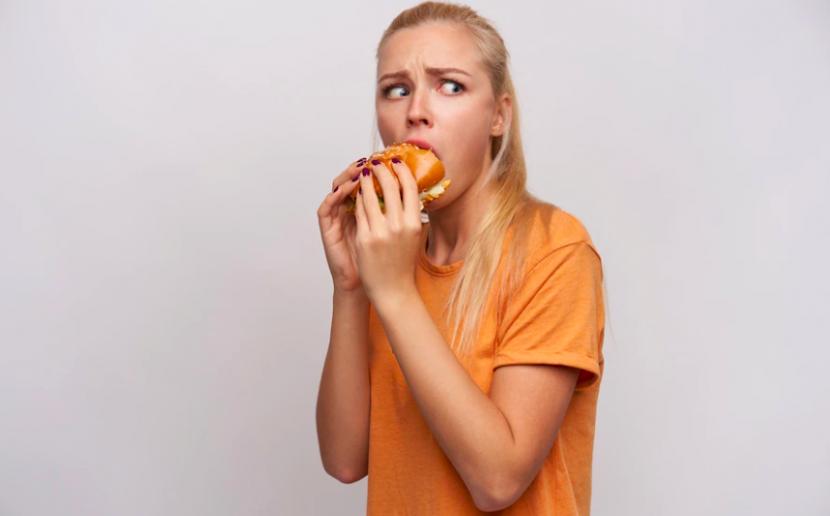 Perempuan menyantap makanan dengan rasa bersalah (ilustrasi). Puasa intermiten tampaknya dapat memicu orang menjadi binge-eating di masa depan. 