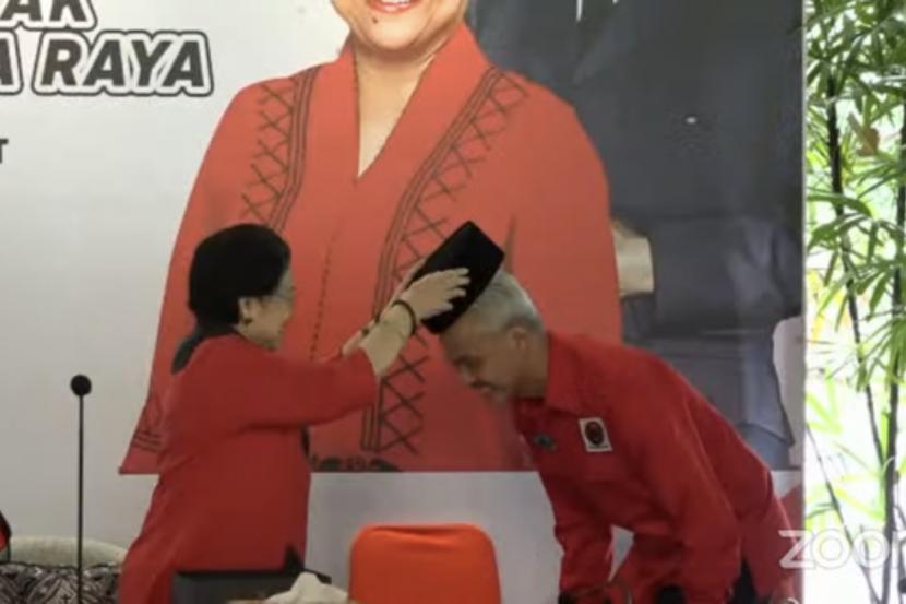 Tangkapan layar Ketua Umum PDIP Megawati memberikan peci hitam kepada Ganjar Pranowo sebagai simbol deklarasi Capres PDIP. Ketum PDIP Megawati Soekarnoputri dan capres Ganjar Pranowo menyambut kedatangan PPP..