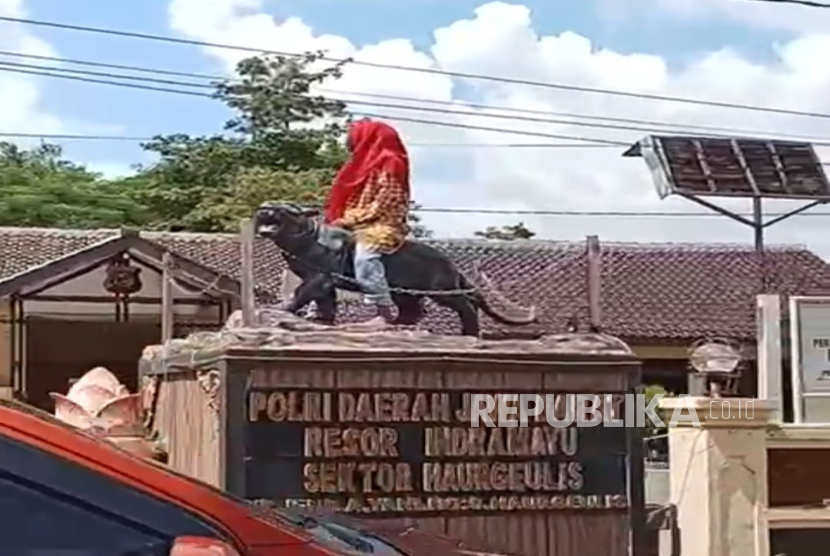 Tangkapan layar seorang wanita menduduki patung macan lodaya di Mako Polsek Haurgeulis, Kabupaten Indramayu. 