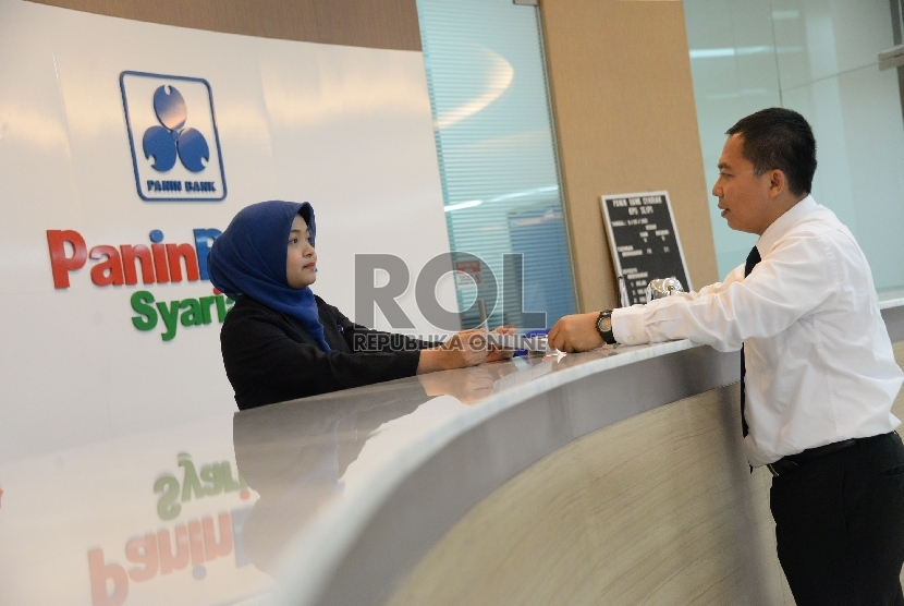 Teller melayani nasabah di salah satu banking hall Panin Bank Syariah. Jakarta.