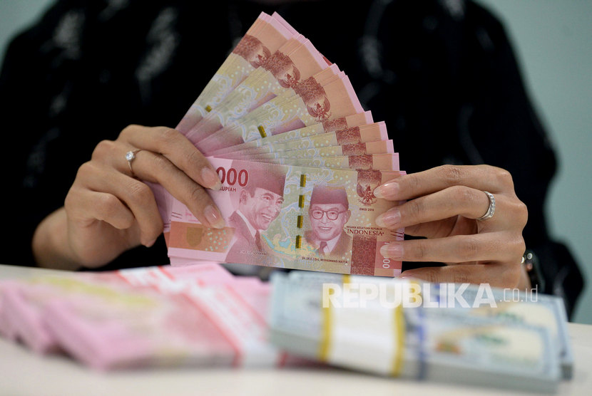 Teller menghitung uang rupiah di Bank Mandiri, Jakarta. Nilai tukar rupiah terhadap dolar AS tertekan isu terus meningkatnya jumlah kasus Covid-19 di Indonesia. (ilustrasi)
